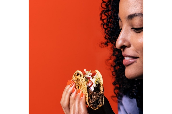 A woman eating a taco with cultured meat.